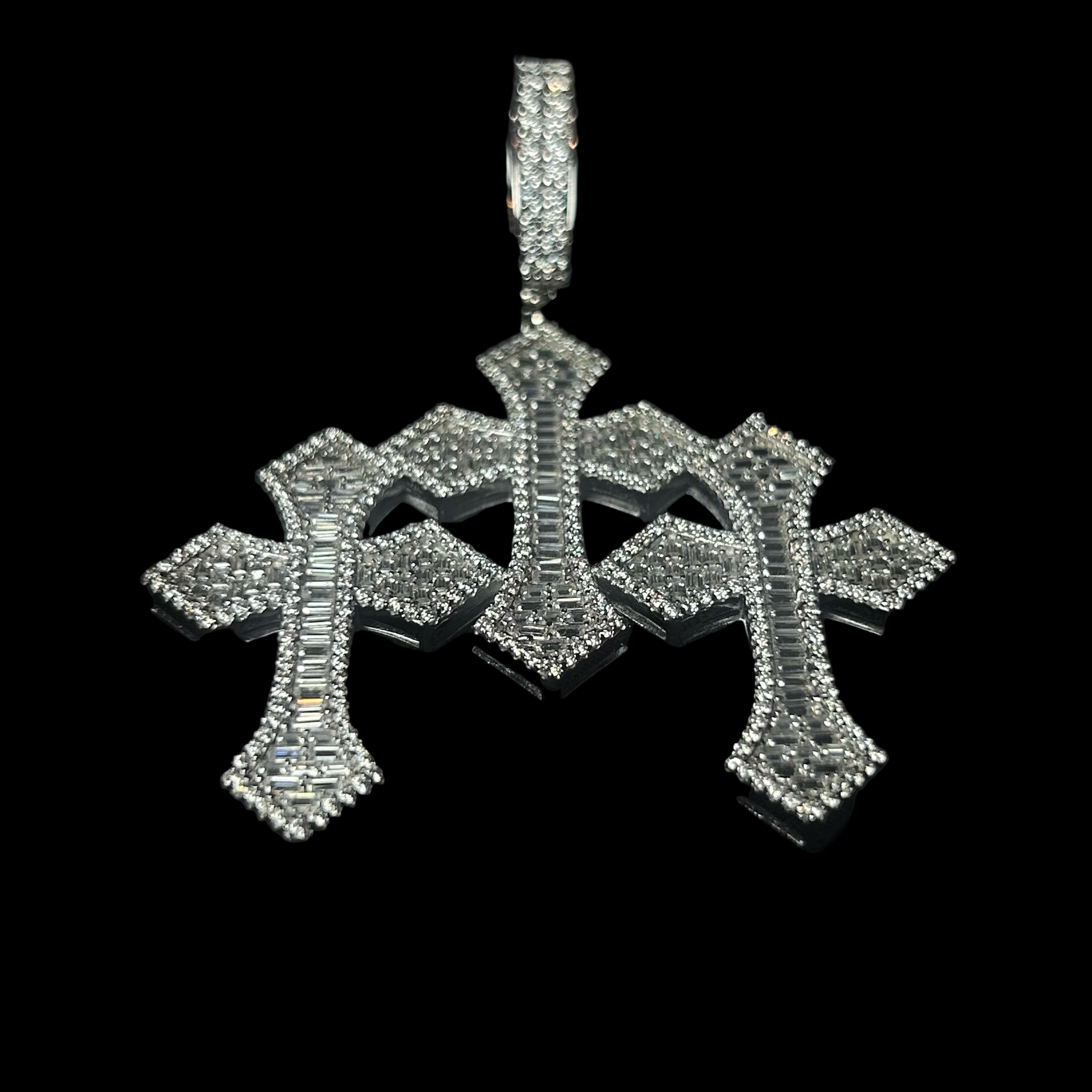 Silver cross pendant with clear stones on a black background, branded 'CRUDDA'.
