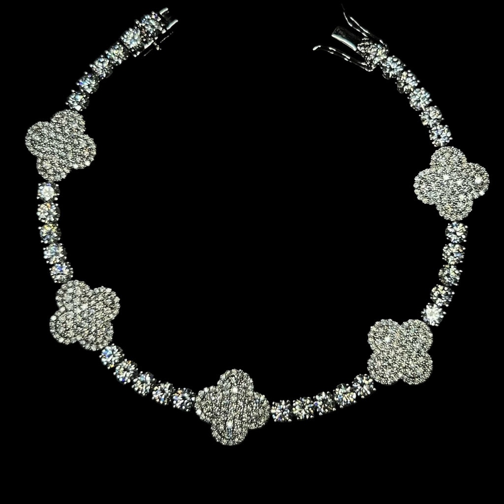 Silver floral necklace with clear stones on a black background, featuring the brand 'CRUDDA'.