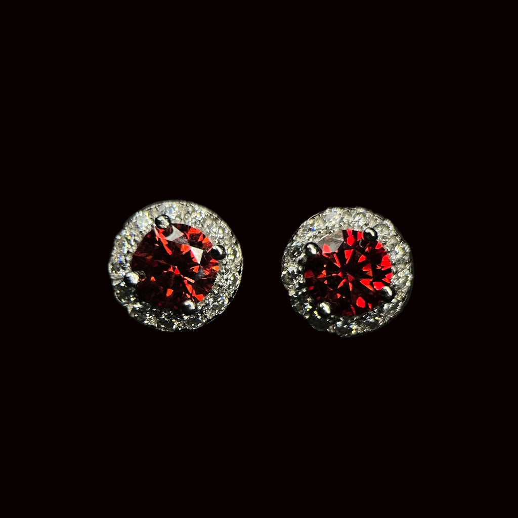 Pair of round earrings with red gemstones and silver accents on a black background